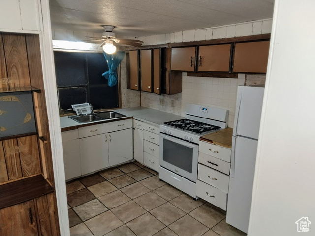 Kitchen featuring tasteful backsplash, light tile patterned floors, white appliances, ceiling fan, and sink