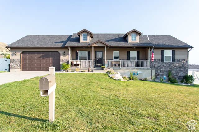 View of front of home with covered porch, a garage, and a front lawn