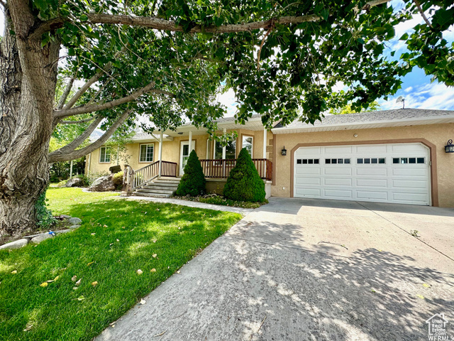 Ranch-style house with a garage, a front yard, and covered porch