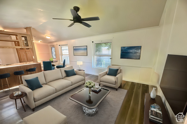 Living room featuring wood-type flooring and ceiling fan. Virtually staged