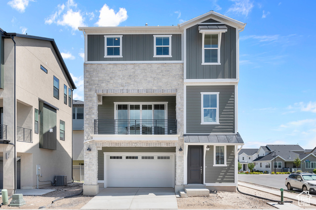 View of front of house with a garage, central AC unit, and a balcony