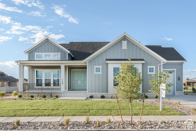 View of front of house featuring a porch, a garage, and a front lawn