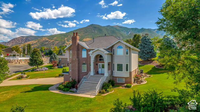 View of front of house with a mountain view and a front lawn