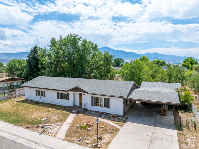 Ranch-style home with a front lawn, a mountain view, and a carport