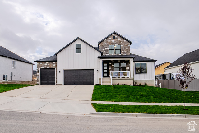 Modern farmhouse style home with covered porch, a front lawn, and a garage