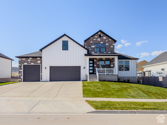 Modern farmhouse with a garage, a front lawn, and covered porch