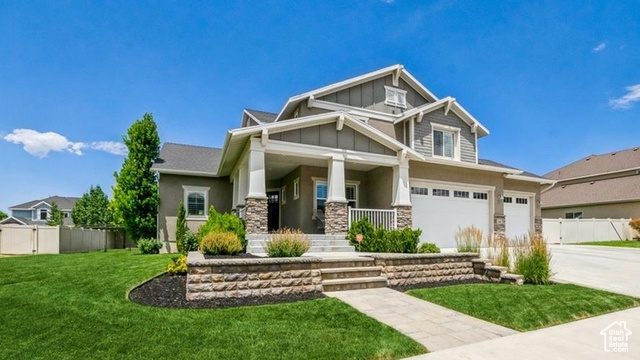 Craftsman-style house featuring a front lawn, covered porch, and a garage