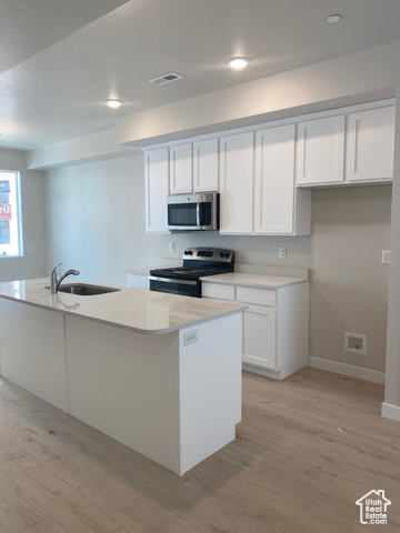 Kitchen with white shaker cabinets, stainless steel appliances, and white quartz counters.