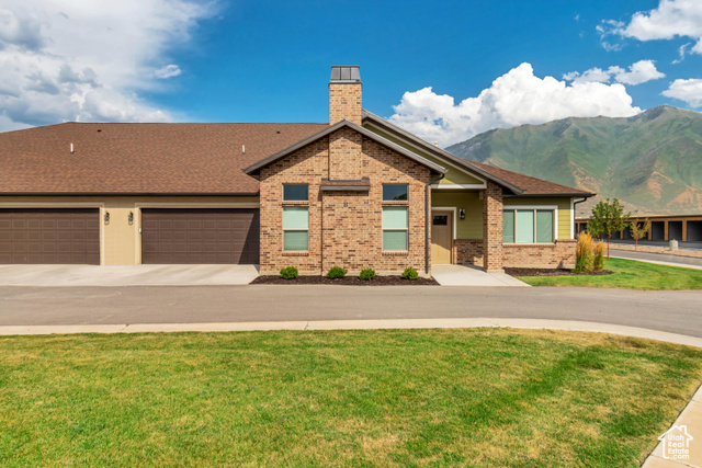 View of front facade featuring a mountain view, a garage, and a front yard