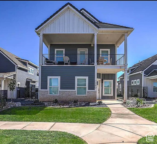 View of front of home with a front lawn and a balcony