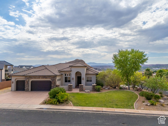 Mediterranean / spanish-style home with a garage and a front lawn