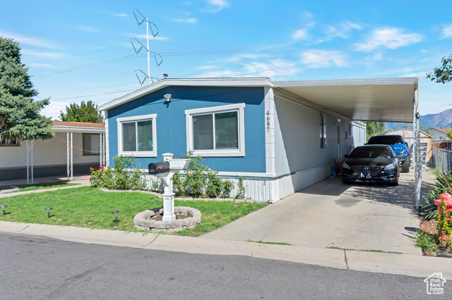 Manufactured / mobile home with a front lawn and a carport