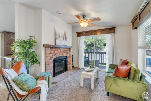 Living room featuring vaulted ceiling, a brick fireplace, ceiling fan, and carpet floors