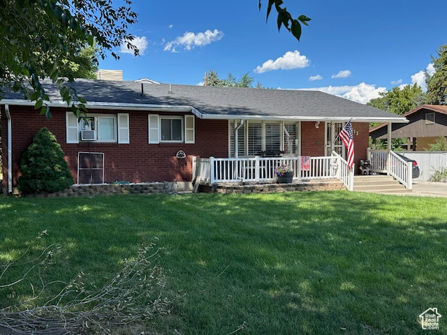 Back of house featuring a lawn, covered porch, and cooling unit