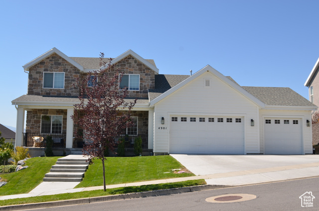 View of front of home featuring a front lawn, a garage, and covered porch