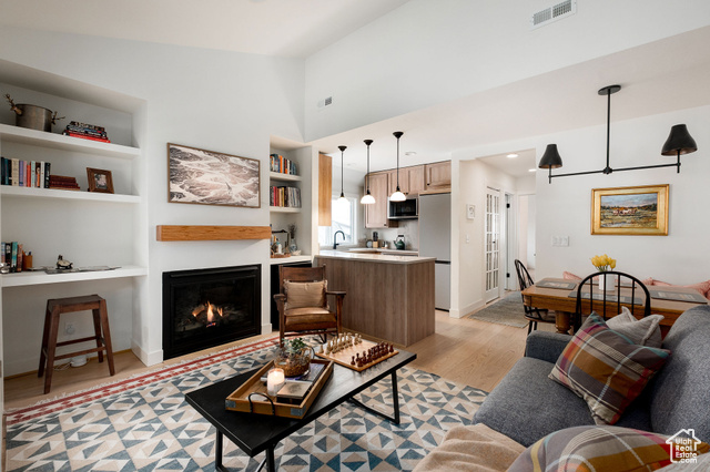 Living room with vaulted ceiling, light hardwood / wood-style flooring, built in shelves, and sink