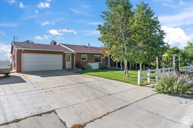 Single story home featuring a garage and a front yard