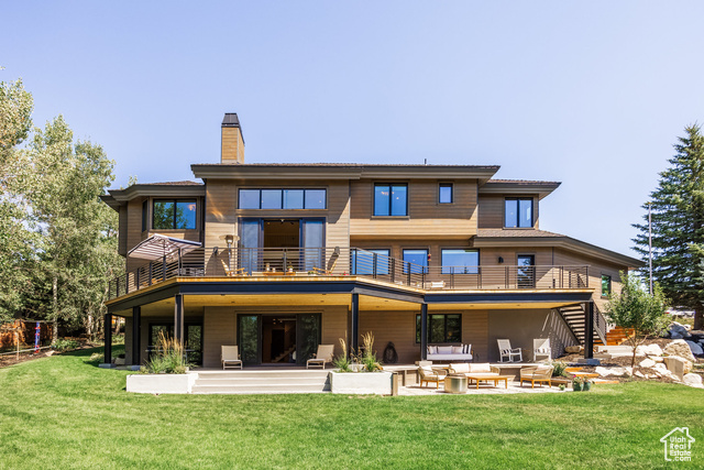 Back of property with a lawn, a patio area, a balcony, and an outdoor hangout area