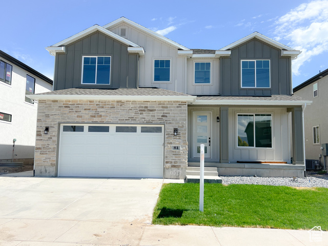 View of front of property featuring cooling unit, a garage, and a front yard