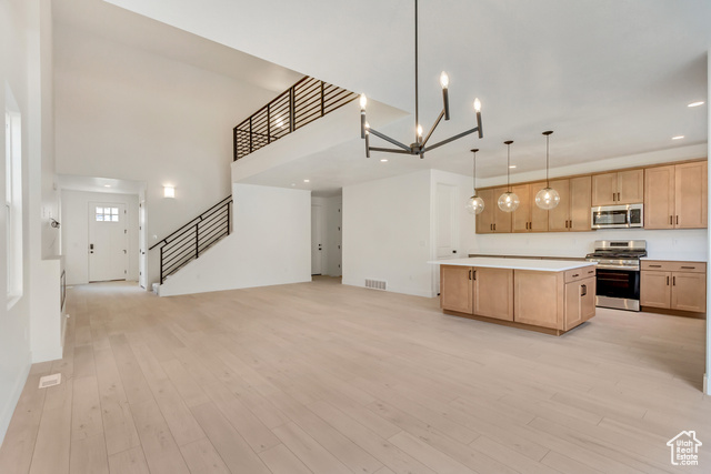 Kitchen featuring decorative light fixtures, appliances with stainless steel finishes, light brown cabinets, and light hardwood / wood-style floors