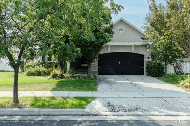 Obstructed view of property with a garage and a front lawn