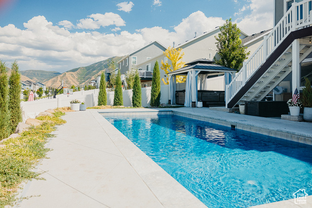 View of swimming pool with a patio area, a mountain view, and a gazebo