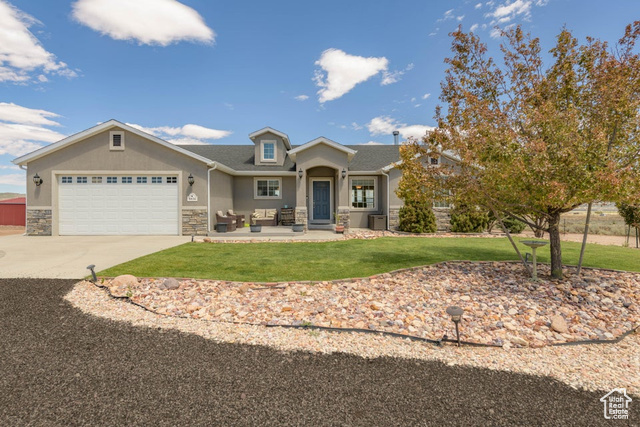 View of front of property with a garage, a front lawn, and central AC unit