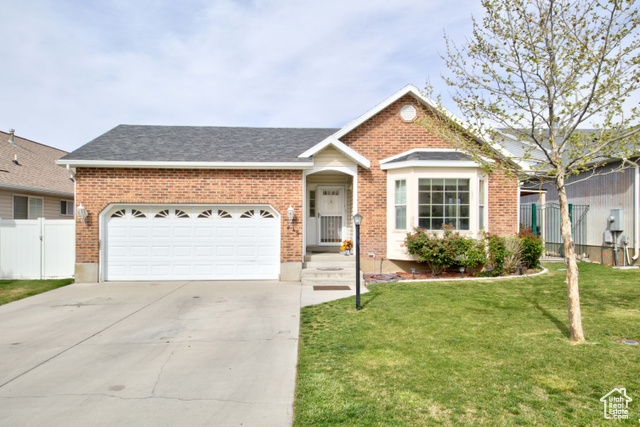 Ranch-style home featuring a garage and a front lawn