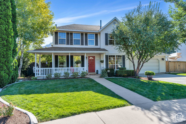 View of front of property with a porch, a garage, and a front yard