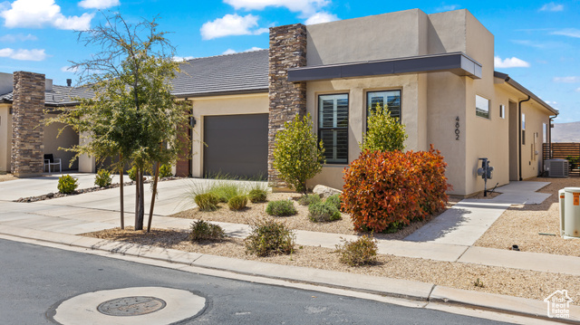 View of front of home with a garage and central AC