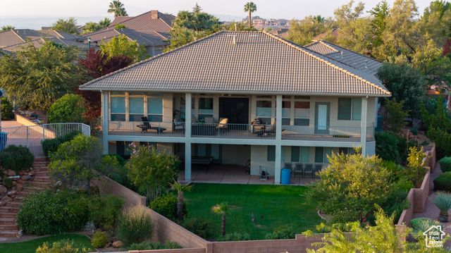 Rear view of house with a lawn, a patio, and a balcony