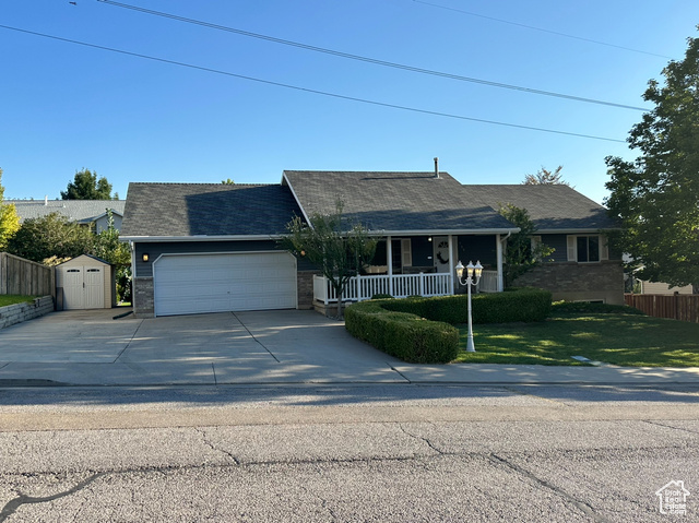 Single story home with a storage shed, a front lawn, and covered porch