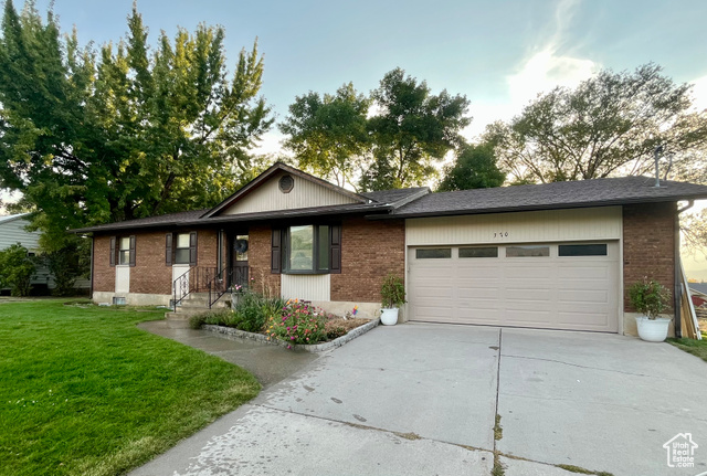 View of front of property with a garage and a front lawn