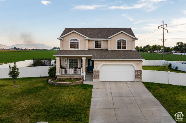 View of front of house with covered porch, a mountain view, a garage, and a front lawn