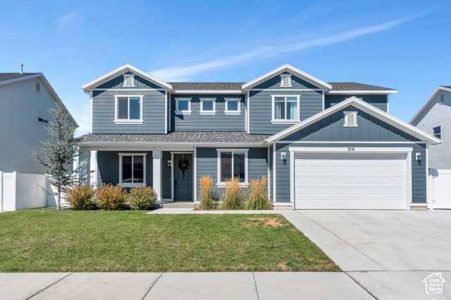 Craftsman-style home with covered porch, a front yard, and a garage