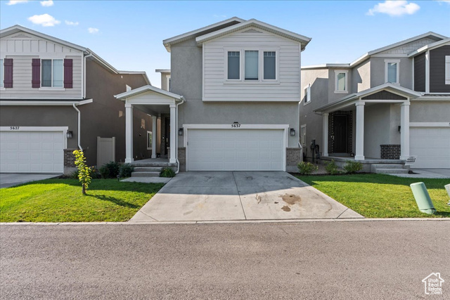 View of front facade featuring a front yard and a garage