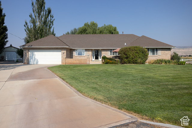 Single story home with a garage and a front lawn