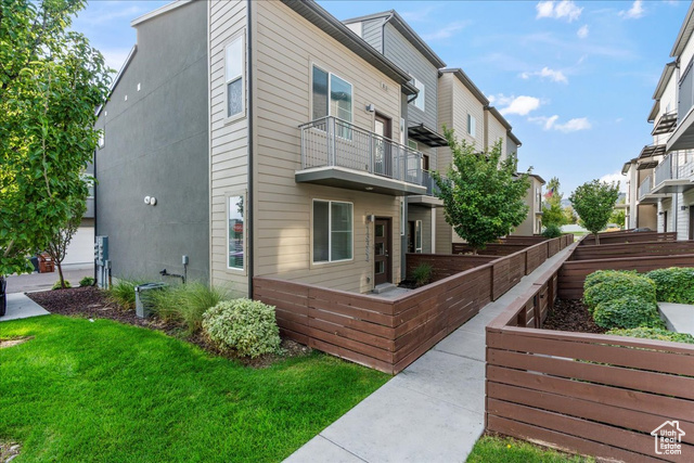 View of side of home featuring a lawn and a balcony