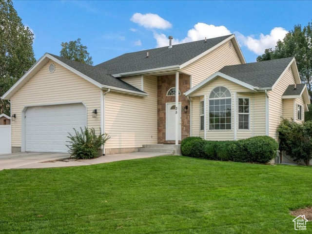 View of front facade featuring a front lawn and a garage