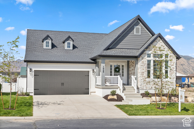 View of front of property featuring covered porch, a front yard, and a garage