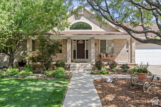 Ranch-style home featuring a garage, a front lawn, and a porch