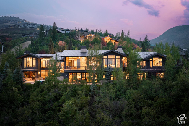 Back house at dusk featuring a balcony and a mountain view