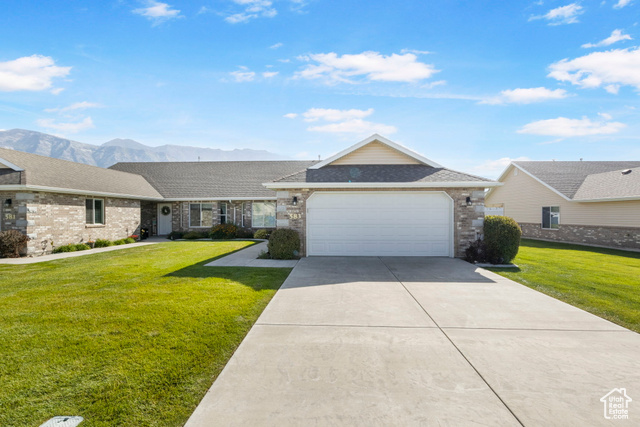 Ranch-style home with a mountain view, a garage, and a front yard