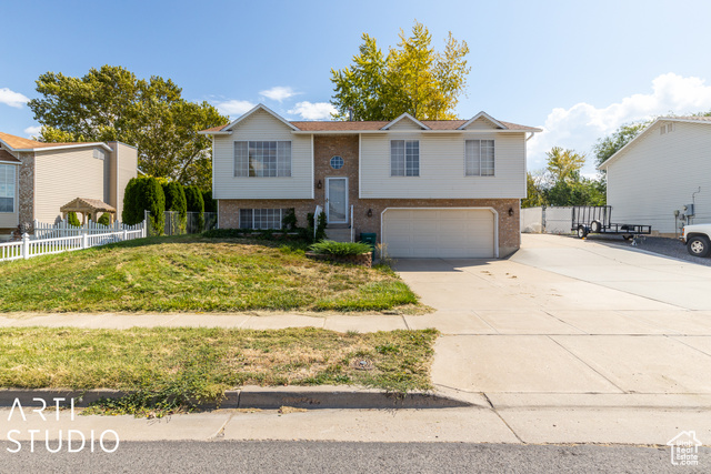 Raised ranch featuring a garage and a front yard