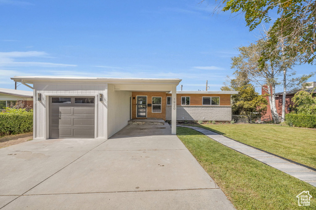 View of front of property featuring a garage, a carport, and a front yard