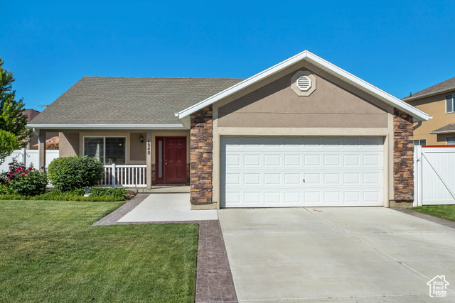 Ranch-style house featuring a front lawn, a garage, and covered porch