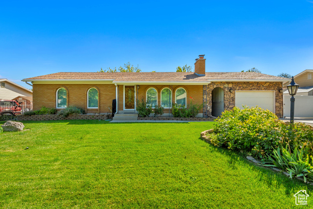 Single story home featuring a garage and a front yard