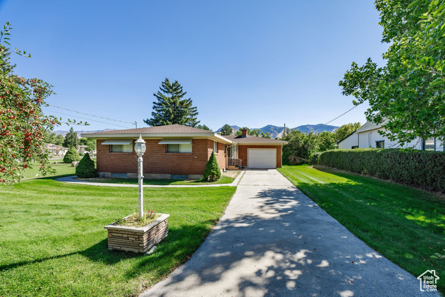 View of front facade with a mountain view, a garage, and a front yard