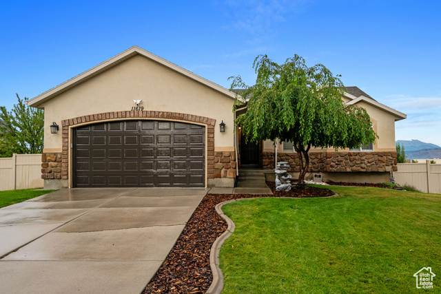 View of front of property featuring a mountain view, a garage, and a front lawn