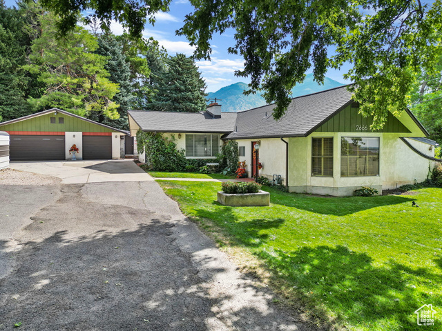 Single story home featuring a garage, a front lawn, and an outbuilding